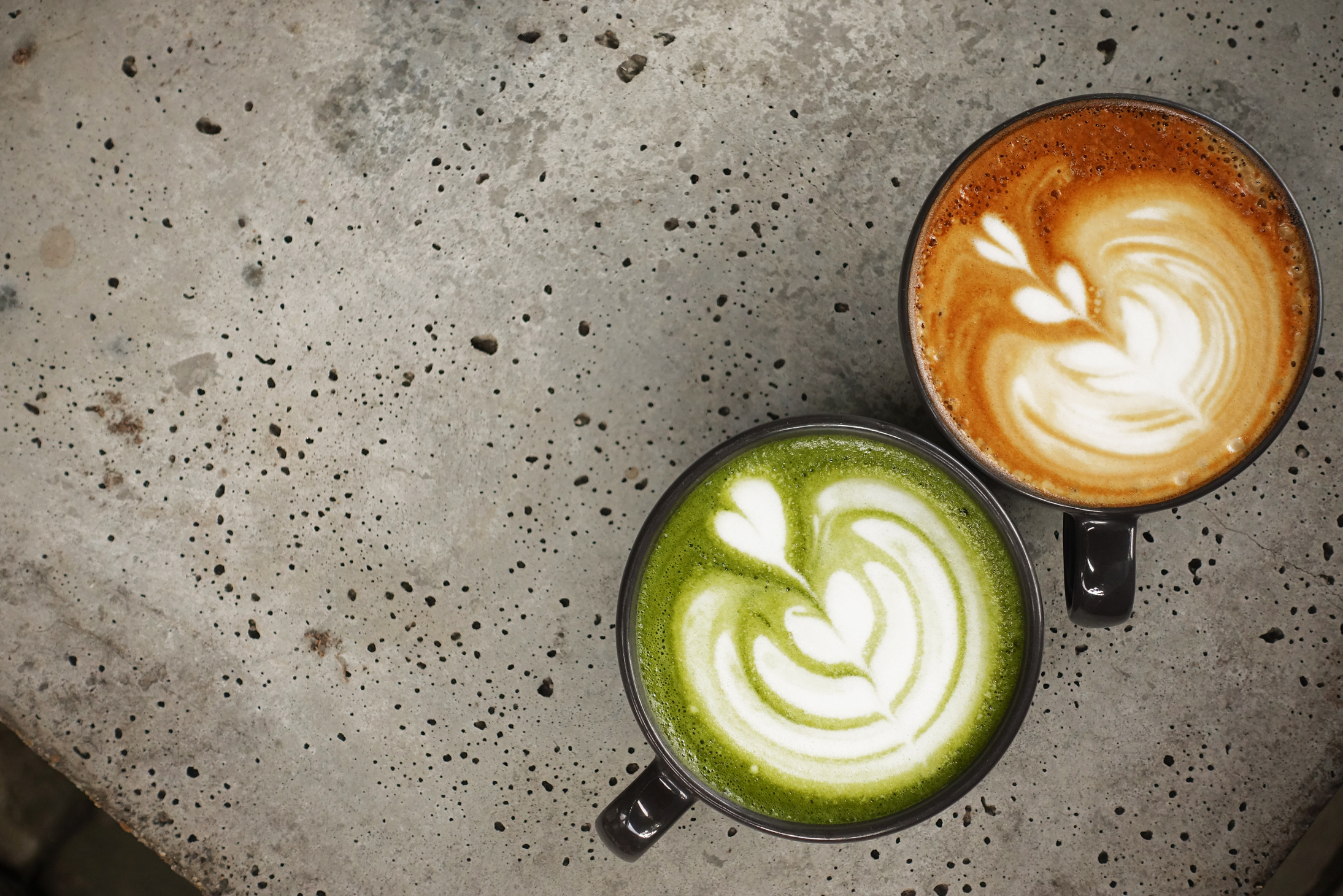 A cup of green tea matcha latte and cup of latte art coffee